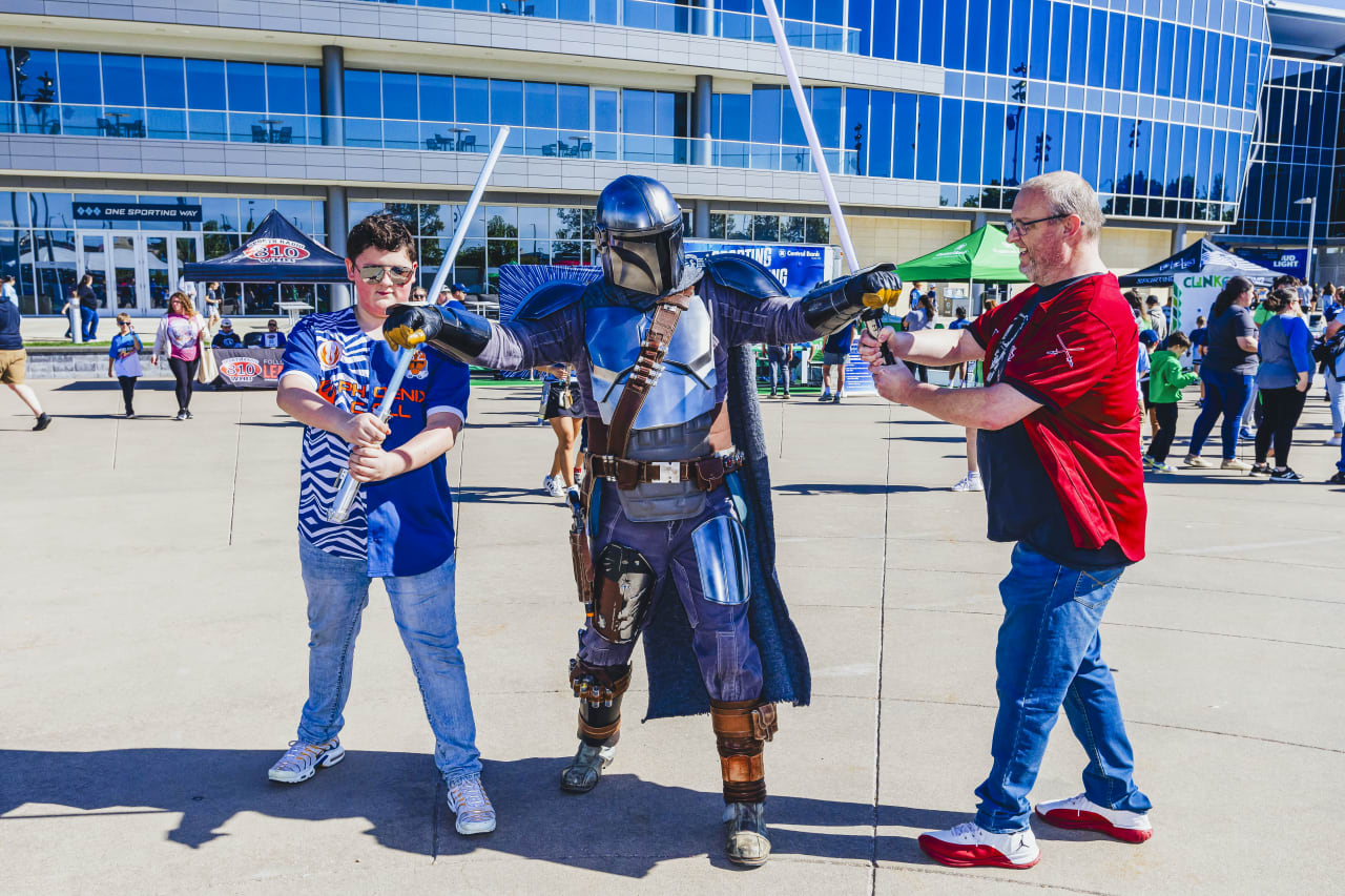 Two fans strike a pose with a Star Wars character on Mazuma Plaza before the game on Sunday.