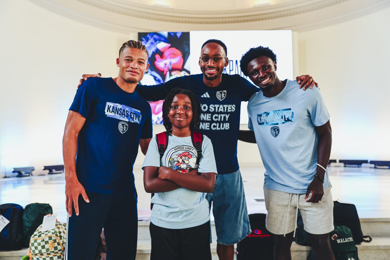 Sporting KC players Mason Toye, Zorhan Bassong and Stephen Afrifa smile for a photo with a student.