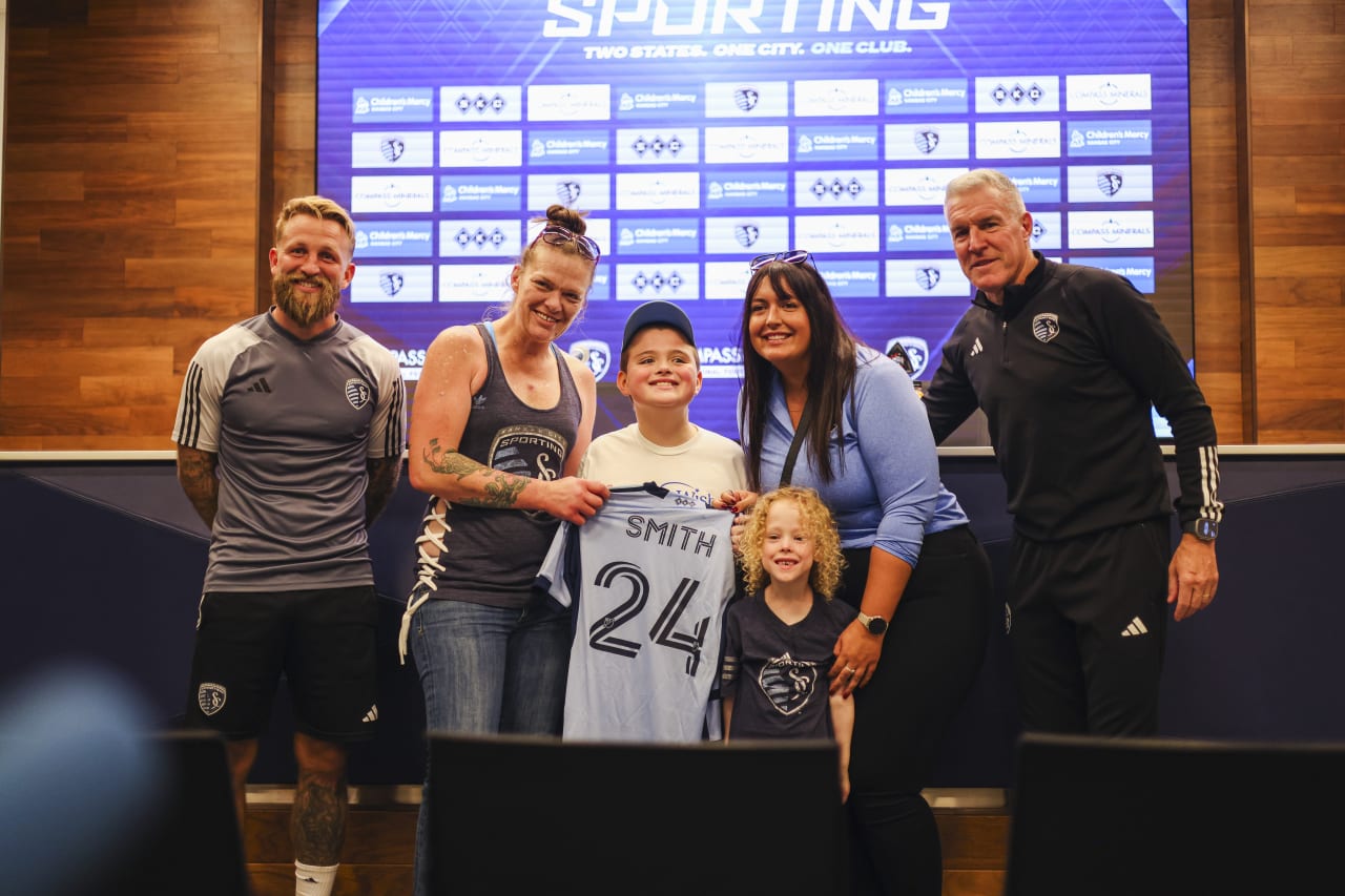 Johnny Russell, Miles Smith and his family, and Head Coach Peter Vermes take a picture in front of the media on Oct. 3..