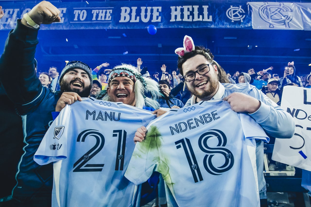 Two Sporting KC fans pose with jerseys received from Sporting KC players after the game