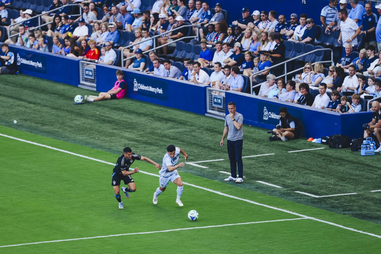 Sporting KC midfielder Manu Garcia runs with the ball as Sporting KC interim head coach Kerry Zavagnin and fans watch on.