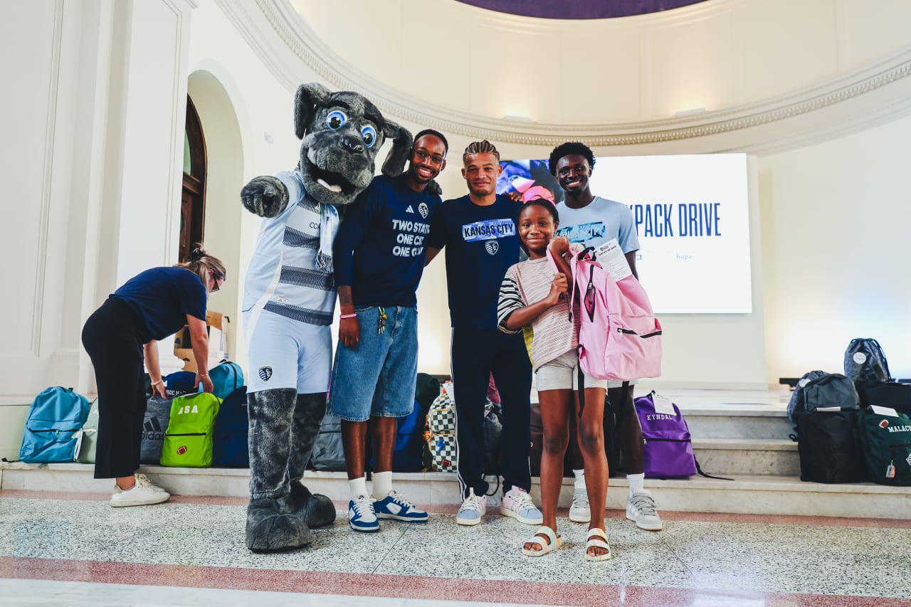 Sporting KC Mascot Blue and Sporting KC players Mason Toye, Zorhan Bassong and Stephen Afrifa smile for a photo with a student.