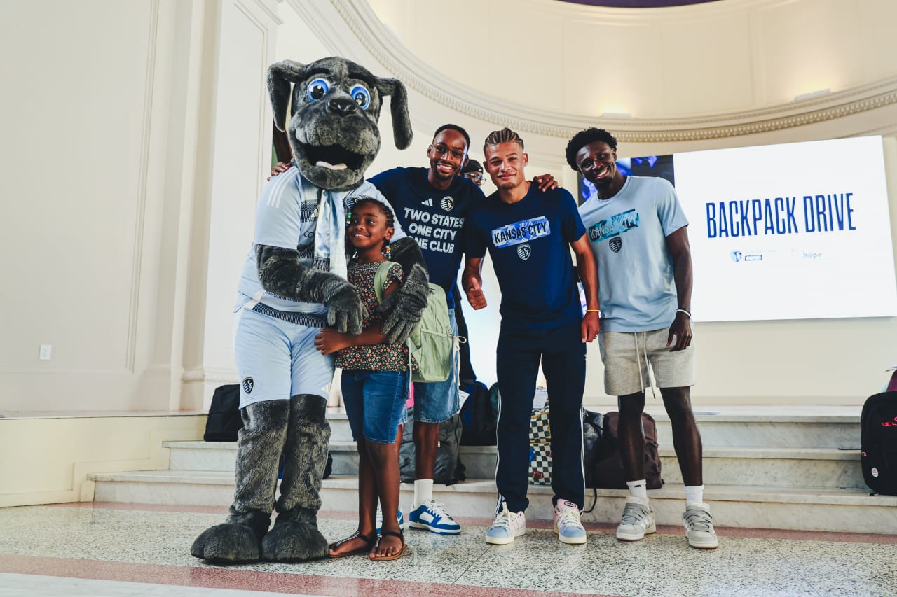 Sporting KC Mascot Blue and Sporting KC players Mason Toye, Zorhan Bassong and Stephen Afrifa smile for a photo with a student.