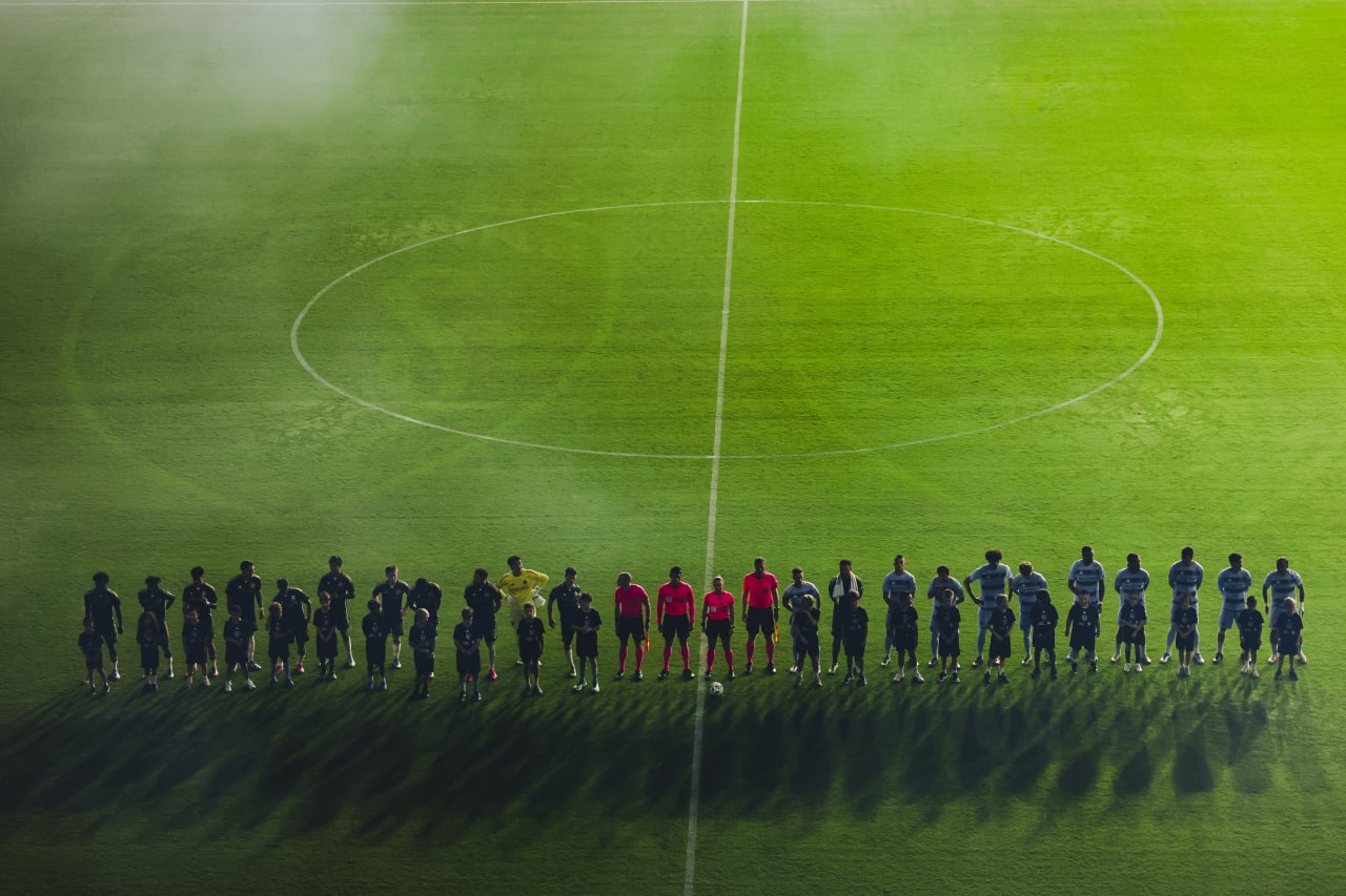 Players stand for the national anthem as the lights put them in a shadow.