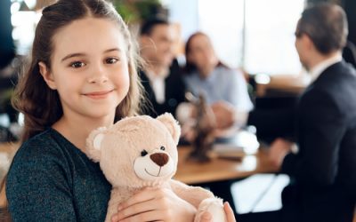 Happy little girl is hugging teddy bear at office of family lawyer. Registration of guardianship. Family in office of family lawyer.